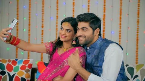 Indian couple happily posing while capturing selfies during the festive season Foto stock