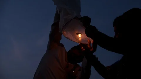 Indian couple is lighting flying lanterns in the sky Stock Footage 118426833