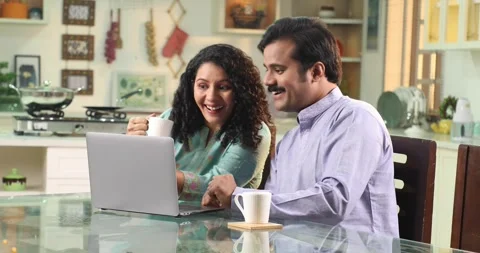 Indian couple sitting at dining table drinking coffee at home 스톡 동영상 255423789