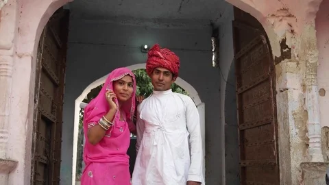 Indian couple standing and posing for camera in from of their old traditional ho Stock Footage 70276094