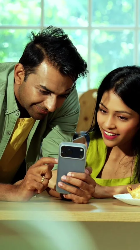 Indian couple surfing internet checking photos on smartphone in kitchen Stock Footage 342689049