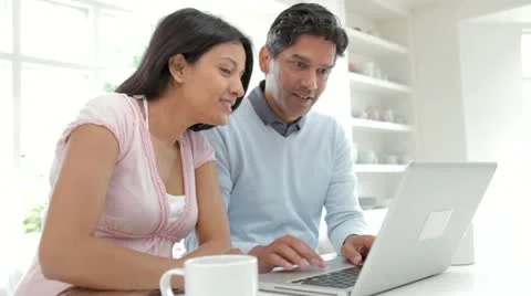 Indian Couple Using Laptop Computer In Kitchen At Home Stock Footage