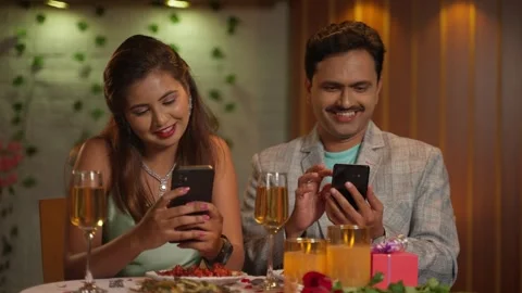 Indian couples at romantic candlelight dinner busy using mobile phone at Stock Footage 260059560