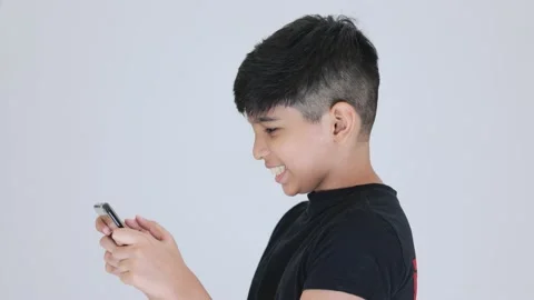 Indian cute boy playing games with his smartphone and smiling he is also cur Stock Footage 159594620