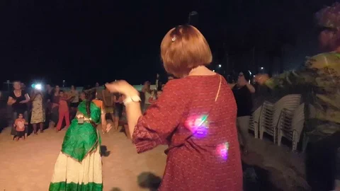 Indian dance instructor demonstrates dance in circle of people on the beach Stockbeeldmateriaal 80632604