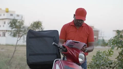 Indian delivery boy checking customer list by seeing mobile phone on road - Stock Footage 169236509