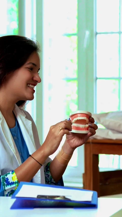 Indian dentist teaching young boy proper brushing techniques using a denture Stock-Footage 342432805