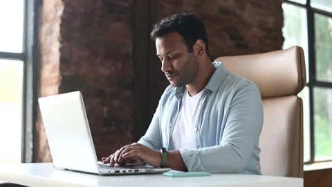 Indian developer guy is working with a laptop sitting at the desk indoors Stock Footage 157207947
