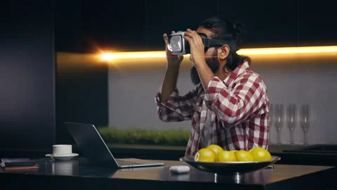 Indian developer testing VR headset while creating new game on laptop at home Stock Footage 316836557