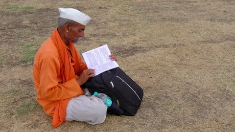 Indian devotee sitting and reading Book during pandharpur wari. Stock Footage 282671889