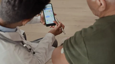 Indian Doctor Explaining Health Data on Smartphone to Senior Man Stock Footage 339628702