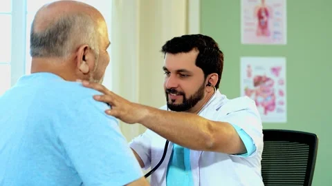Indian Doctor using a stethoscope to examine an elderly patient in OPD Stock Footage 342425616