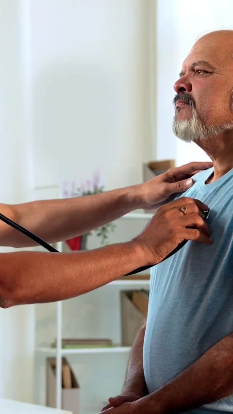 Indian Doctor using a stethoscope to examine an elderly patient in OPD Stock Footage 342427384