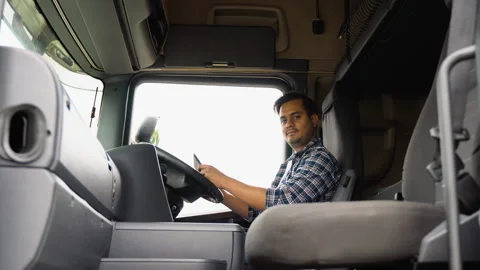 Indian driver in cabin of big modern truck with tablet Stock Footage 251835546