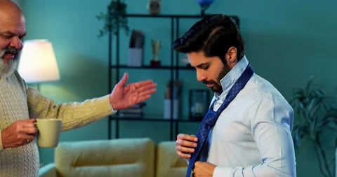 Indian Elderly dad assists his grown son as he prepares confidently for work Video stock 342777670