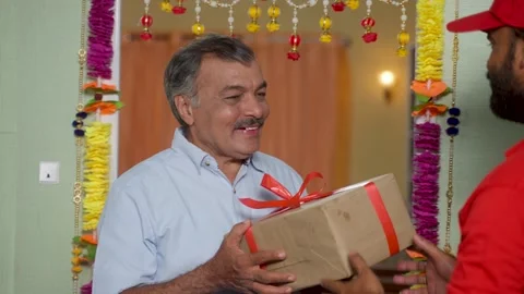 Indian elderly senior man receiving parcel or box from delivery person at home - Stock Footage 256623685