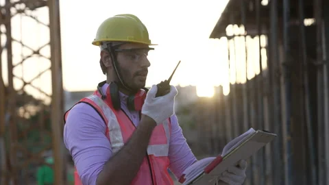 Indian engineer operate with radio talking to control work at construction. Vidéo 161875173