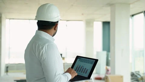 Indian engineer reviewing construction project data with a laptop on-site Stock Footage 285670203
