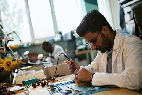 Indian Engineer Soldering Microchip Component in Robotics Laboratory Stock Photos
