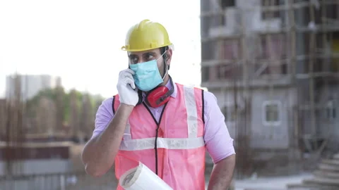 Indian engineer talking on phone while hold blue prints at construction. Видео 161814602