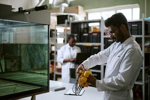 Indian Engineer Testing Robotic Device near Water Tank in Laboratory Stock Photos