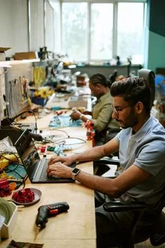 Indian Engineer Typing on Laptop in Hardware Workshop Stock Photos