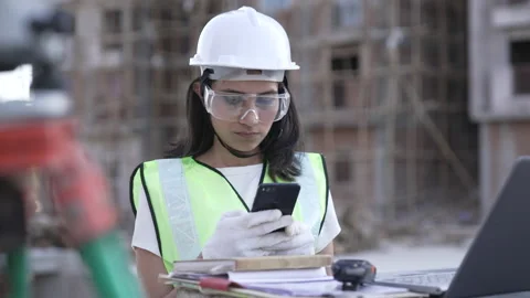 Indian Engineer use phone while check details in laptop at Construction site. Видео 161810990