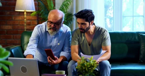 Indian experienced old dad grown son celebrating share trading profit indoors Stock Footage 342778444
