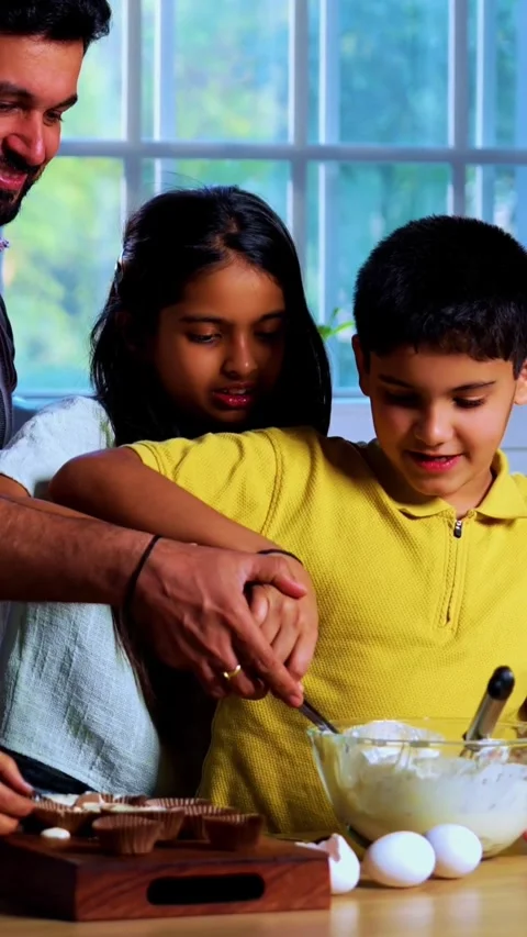 Indian family making cake batter together while parents and kids enjoy baking Stock Footage 342804100