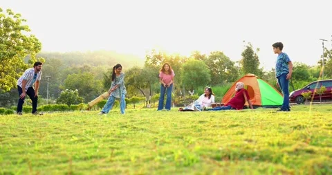 Indian family playing cricket while camping outdoors bonding with laughter Stock Footage 342840713