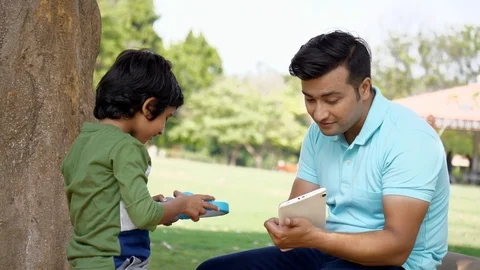Indian father and son using a tablet with blue headphones while spending time... Stock-Footage 118515995