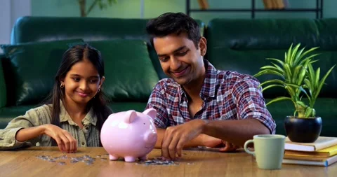 Indian father Teaching daughter saving coins in piggy bank, financial education Stock-Footage 342845542
