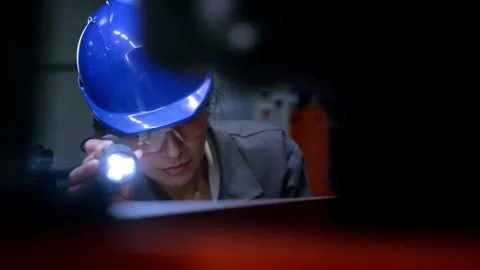 Indian female engineer holding a flashlight and examining machinery in a factory Stock Footage 296287078