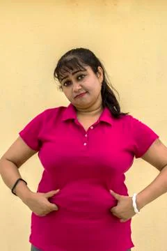 Indian female model looking down unhappy with her fat belly in yellow backgro Stock Photos