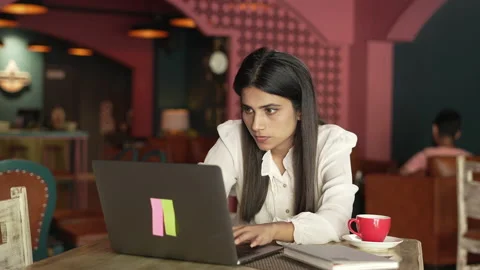  Indian female professional using laptop and doing research sitting at cafe. Видео 232575798