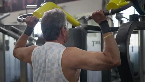 Indian fit aged man performs a shoulder exercise using modern machine in a gym Stock Footage 341856485