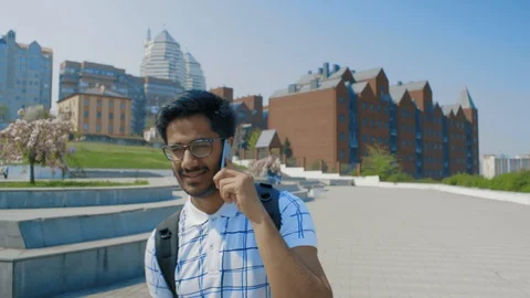 Indian Guy with Glasses Talking on the Phone, Walking in the City Park Stock Footage 111145507