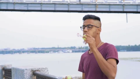 Indian Guy in Glasses Trying to Puff Soap Bubbles on the Wind Stock Footage 95409612