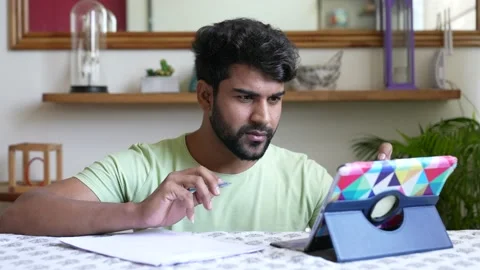 Indian guy working on tablet and notepad at home office. Stock-Footage 154159354