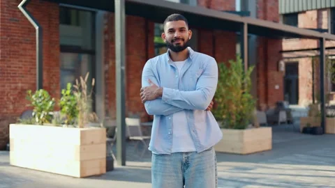 Indian handsome man posing on camera with arms crossed while standing outdoors Video stock 250073134