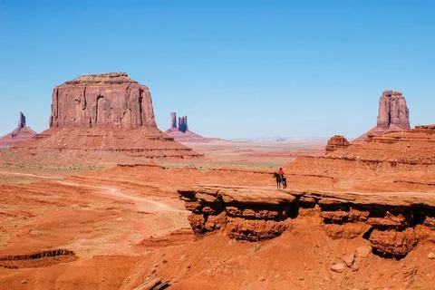 An Indian on a horse in front of a red rock formations in Monument Valley ... Stockfoto's