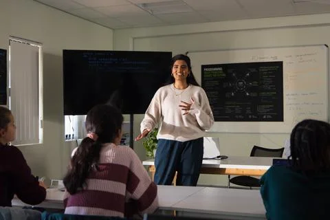 Indian instructor presenting code lesson in room while youth female students 스톡 사진