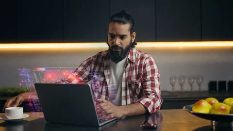 Indian IT specialist coding on laptop with futuristic holographic screen at home Video stock 329506307