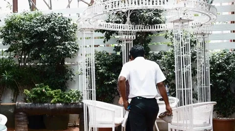 Indian janitor cleans up table for asian customer Stock Footage 65889587