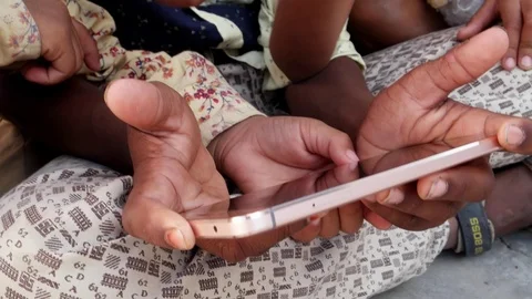 Indian kids sharing a touch screen phone mobile screen, handheld closeup 스톡 동영상 69871916