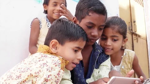 Indian kids sharing a touch screen phone mobile screen, handheld Stock Footage 69872948