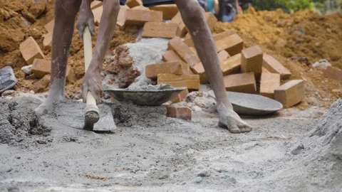 Indian labourer or worker loading the cement onto the head pan with a hoe Stock Footage 119981455
