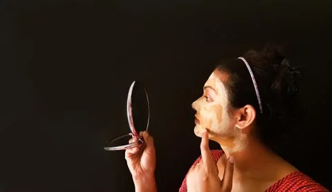 An indian lady with face pack applied in half dried condition checking her fa Stock Photos