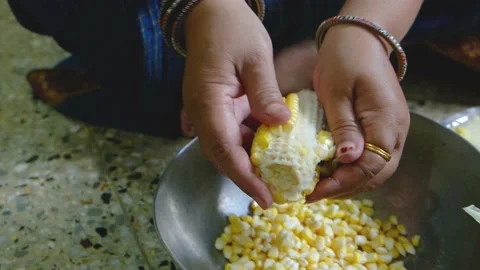 An Indian lady is separating the corn from the corn cob. Stock Footage 161950210