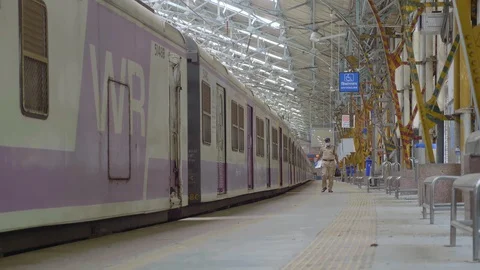 An Indian male constable walking on a empty platform next to local train Stock Footage 129897089